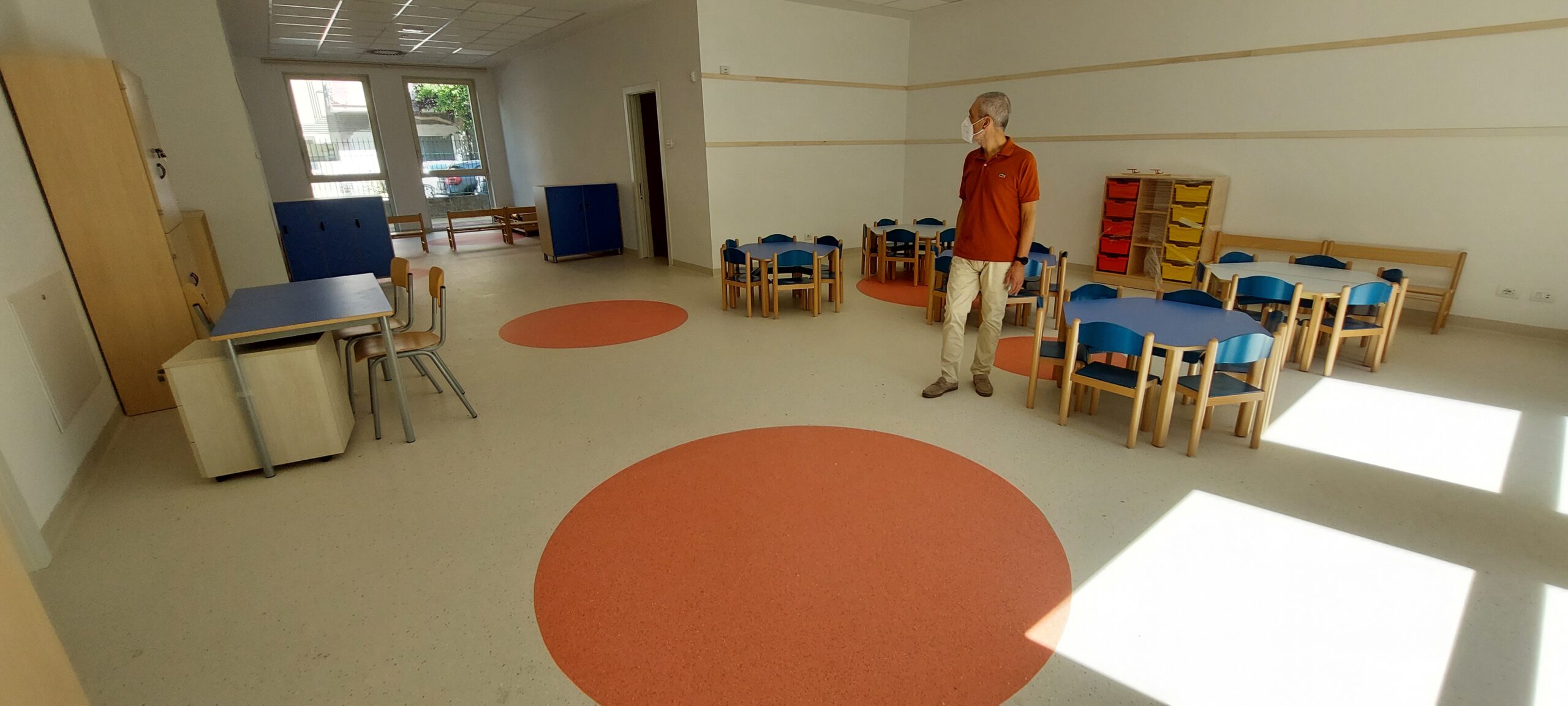 Un'aula della scuola dell'infanzia con tavolini rotondi ognuno con cinque seggioline