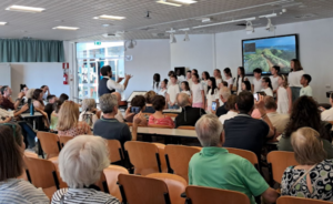Il coro delle nostre scuole primarie schierato in aula magna segue con attenzione i gesti del direttore